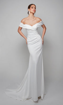 A woman stands against a plain light background wearing the Long White Dress: Alyce 7059 in Diamond White, a fitted satin formal gown featuring an off-shoulder design and a slight train.