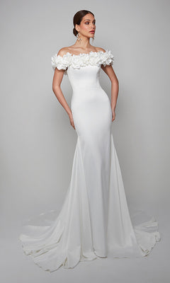 A woman wears the Alyce 7061 long formal dress in diamond white, featuring an off-the-shoulder neckline with floral details and a flowing train for timeless elegance.