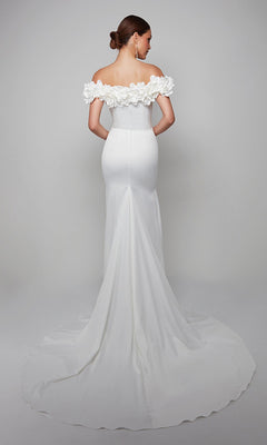 Wearing the Alyce 7061 long formal dress with off-the-shoulder floral detailing and a dramatic train, a woman stands against a plain backdrop, facing away from the camera.