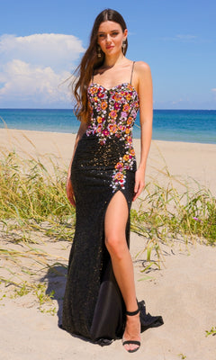 A woman stands on a sandy beach in the Multicolored Sequin Prom Gown: Amelia Couture 7061, featuring a stunning floral bodice and thigh-high slit, with the ocean and blue sky as a dreamy backdrop.