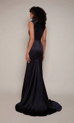 A woman stands facing away, wearing the Long White Dress: Alyce 7067—a sleeveless, floor-length satin sheath gown with a subtle sweep train, set against a plain background.