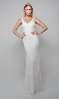 A woman stands against a plain backdrop wearing the Alyce 7075 long ivory dress, a sleeveless sheath with delicate lace appliqués, floor-length silhouette, V-neckline, and headband.