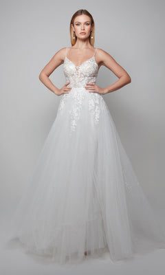 In the Alyce 7079 long ivory dress, featuring a sheer lace-embellished bodice and full tulle skirt, a woman exudes bridal elegance against a plain gray background.