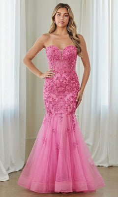 A woman stands indoors in front of white curtains wearing a pink Strapless Mermaid Prom Gown, Amelia Couture 7090.