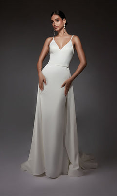 A woman stands against a dark background wearing the Alyce 7090 Long Formal Dress, a sleeveless, floor-length satin gown with a V-neckline that exudes elegance and timeless style.