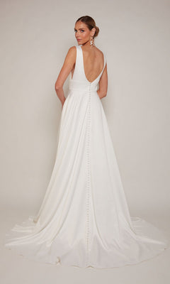 A woman models the Alyce 7096, a long formal white satin dress featuring a graceful train and button details down the back, against a plain background.