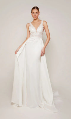 A woman wears the Alyce 7097 long formal dress featuring a sleeveless lace appliqué bodice, deep V-neckline, and flowing skirt against a plain background.