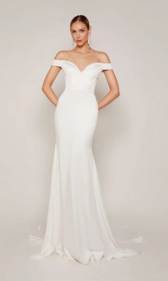 A woman stands against a plain background in the Alyce 7098—a long, fitted white formal dress with off-the-shoulder sleeves and a slight train.