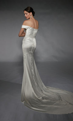 A woman faces away against a plain backdrop, wearing the Alyce 7106 long white dress—an off-the-shoulder satin gown with a fitted silhouette, long train, and detachable overskirt for extra elegance.