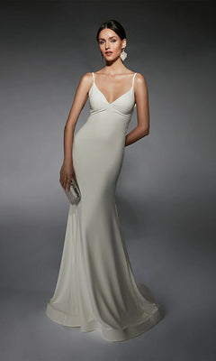 A woman in the Alyce 7108 long ivory dress poses against a dark background, holding a silver clutch and wearing statement earrings.