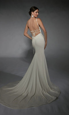 A woman poses in the Alyce 7108 long white dress, a sleeveless formal gown featuring lace-up detailing, a backless design, and a train, against a gray background.