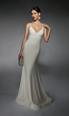 A woman models the Alyce 7108 long white dress—fitted, sleeveless, floor-length with thin straps—holding a small clutch and posing against a gray background.