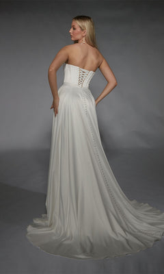 A woman faces away from the camera against a gray backdrop, wearing the Alyce 7111 long white dress—a strapless satin gown with an A-line skirt, lace-up back, and button details.