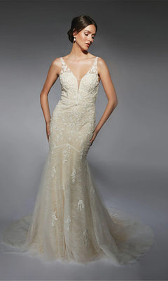 A woman poses against a gray background in the Alyce 7119 long white dress in ivory/champagne, a mermaid bridal gown with beaded lace, sheer straps, a deep V neckline, and delicate floral embroidery.