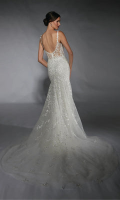A woman in the Alyce 7120 long white dress—fitted, sleeveless, backless, with a sheer floral lace train—stands against a gray background.