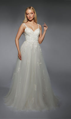 A woman wearing the Long White Dress: Alyce 7124, a floor-length A-line gown with delicate lace appliques, stands against a plain gray background.