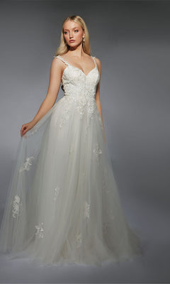 A woman models the Alyce 7124 long white dress, an A-line wedding gown with lace details and lace appliques, standing against a gray background.