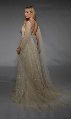 A woman poses in the Long White Dress: Alyce 7134, a floor-length evening gown with sequin embellishments, low back, and sheer cape sleeves, set against a gray backdrop.