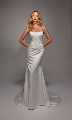 A woman models the Alyce 7139 Long White Dress in Diamond White, featuring a strapless design, corset bodice, and slight train, while standing against a neutral background.