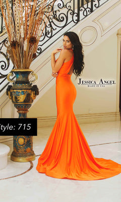 A woman in a fitted, bright orange Cut-Out Long Formal Dress: Jessica Angel 715 stands indoors by an ornate staircase and decorative vase. Text reads "Jessica Angel MADE IN USA" and "Style: 715." This long formal dress makes a striking statement.