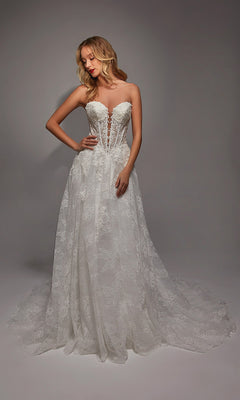 A woman poses against a plain gray background in the Alyce 7154 long white dress, featuring a strapless sheer corset bodice, lace detailing, and a flowing train.