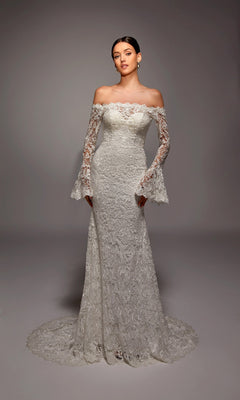 A woman wearing the Alyce 7156 long ivory dress stands in a studio with a neutral background.