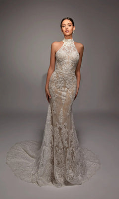 A woman stands against a plain studio backdrop wearing the Alyce 7159, a long white mermaid wedding gown featuring a sleeveless lace design, high neckline, and extended train.