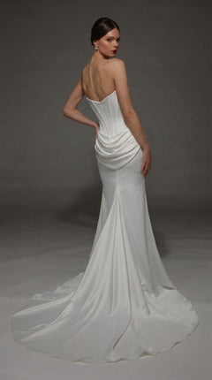 A woman models the Long Wedding Dress: Alyce 7170, featuring a strapless satin design with a fitted corset bodice and a sweeping long train, posed against a gray background.