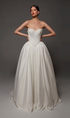 A woman poses in the Alyce 7172 long wedding dress, which features a strapless sweetheart neckline and fitted bodice; the satin ball gown’s full skirt flows elegantly against a plain dark background.