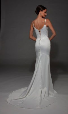 A woman in the Long Wedding Dress: Alyce 7175—a white, fitted, floor-length satin gown featuring thin straps, a graceful cowl neckline, lace-up back, and a slight train—stands against a gray background.