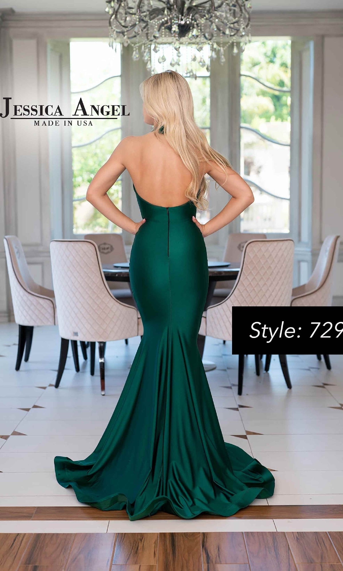 A woman with long blonde hair models the Jessica Angel 729, a fitted emerald green halter mermaid formal dress, standing with her back to the camera in a modern dining room.