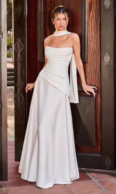 A woman in the Ladivine 7432W Long Prom Dress in Off White, featuring a stretch satin bodice and strapless silhouette, stands before a large wooden doorway, facing forward with one hand resting on the door frame.