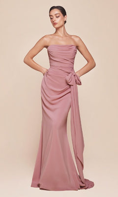 A woman stands against a beige background wearing the Ladivine 7433 Multi-Way Long Chiffon Prom Dress, featuring a strapless mauve design with a draped bodice and large side bow detail.