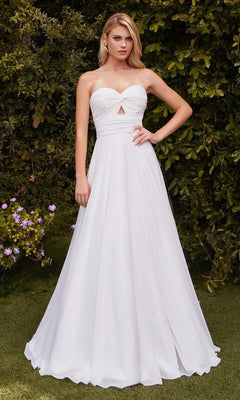 A woman poses outdoors against lush greenery in the Ladivine 7435W Strapless Long White Prom Gown, featuring a sweetheart neckline, front cutout, and off-white color—an affordable formal dress with one hand on her hip.