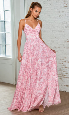 A woman in the Floral-Print Long A-Line Prom Dress: Ladivine 7444 stands indoors, holding out one side of the flowy pink skirt to show its floral pattern and thin straps.