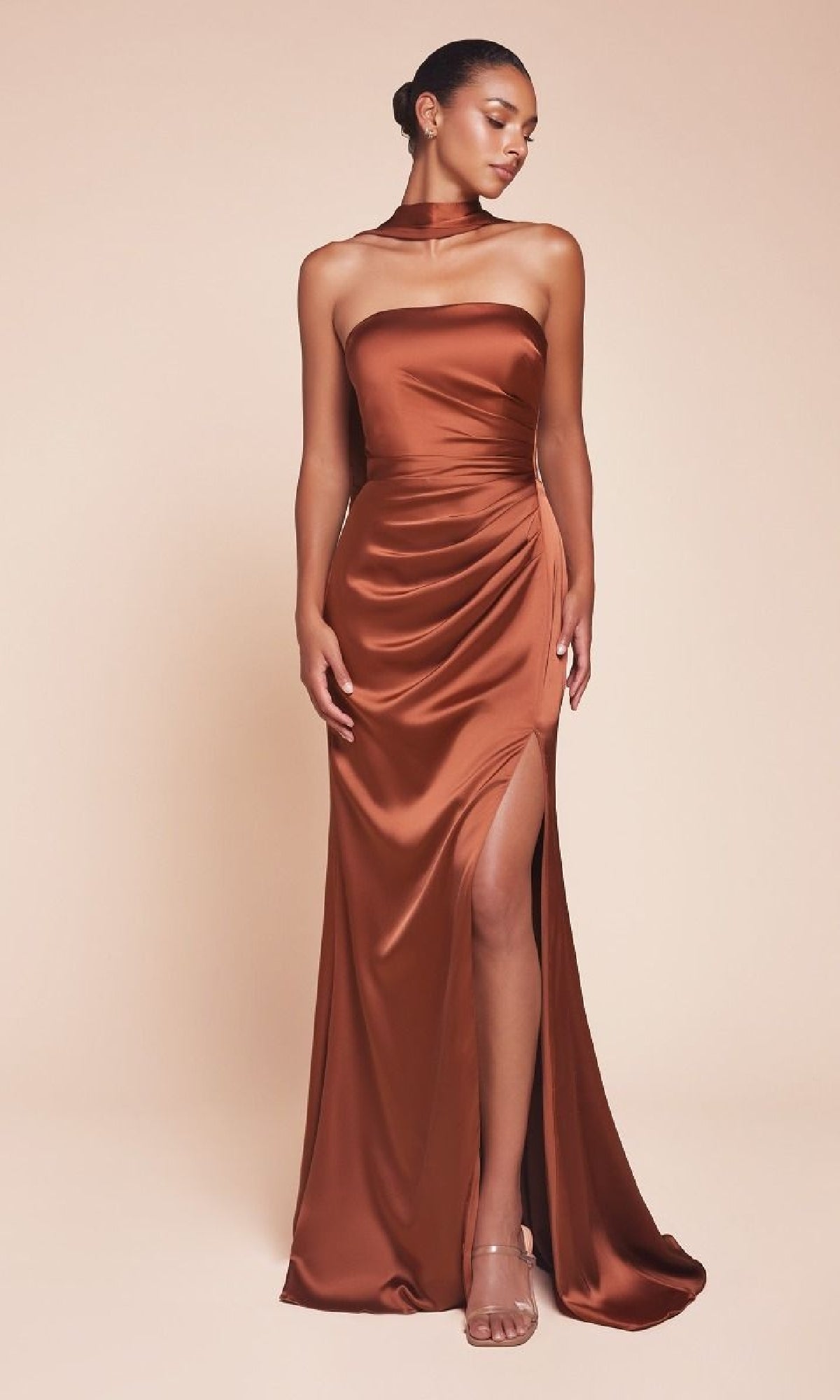 A woman poses against a beige background in the Ladivine 7451 Simple Strapless Long Prom Dress—copper satin, high slit—styled with a matching choker and nude heels.