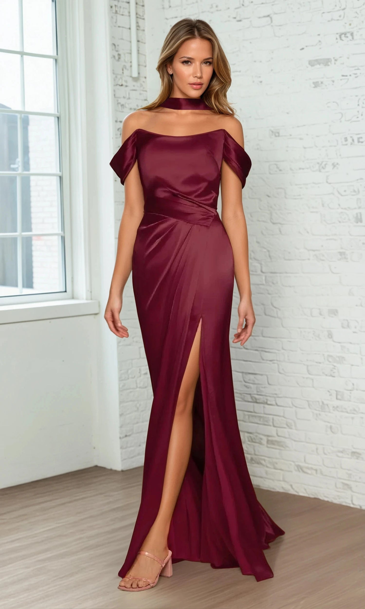 A woman models the Ladivine 7452 Lace-Up Off-Shoulder Prom Dress in burgundy, featuring a thigh-high slit and matching choker, standing indoors on a wooden floor by a window and white brick wall.