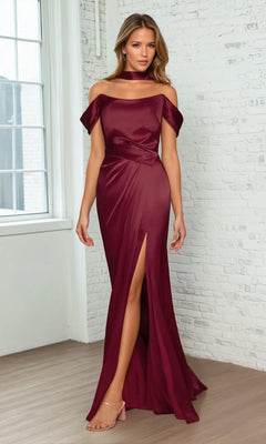 A woman models the Ladivine 7452 Lace-Up Off-Shoulder Prom Dress in burgundy, featuring a thigh-high slit and matching choker, standing indoors on a wooden floor by a window and white brick wall.