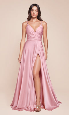 A woman wears the Plus-Size Long A-Line Prom Dress 7485C in blush, featuring a deep V-neckline, thin straps, fitted bodice, and high slit, as she stands against a neutral background.