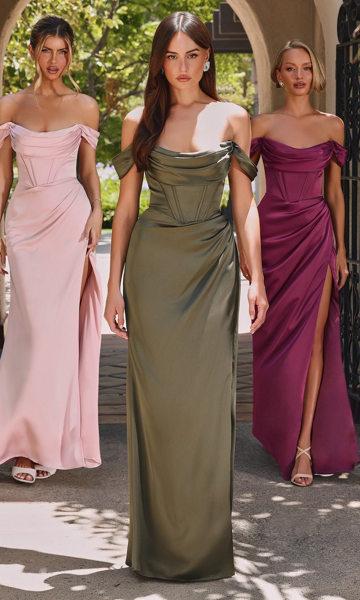 Three women stand outdoors wearing the Ladivine 7492 Off-the-Shoulder Satin Prom Dress in pink, olive green, and magenta, each featuring a high leg slit.