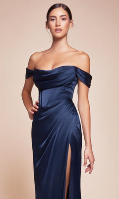 A woman wearing the Cowl-Neck Plus-Size Long Corset Prom Dress 7492C in navy satin, featuring an off-the-shoulder neckline and thigh-high slit, stands against a plain beige background.