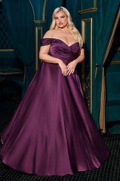 A woman showcases the Empire-Waist Plus-Size Long Prom Dress 7493C in an elegant room with teal drapes and gold accents, wearing a floor-length, off-the-shoulder purple gown.