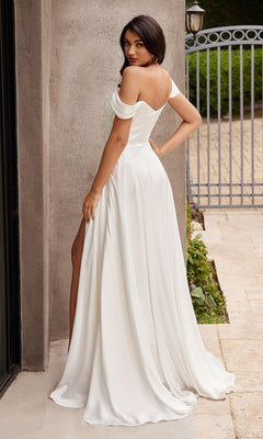 A woman in the budget-friendly Ladivine 7493W Off-Shoulder White Prom Gown with a thigh-high slit stands on a stone patio outdoors, glancing over her shoulder at the camera.