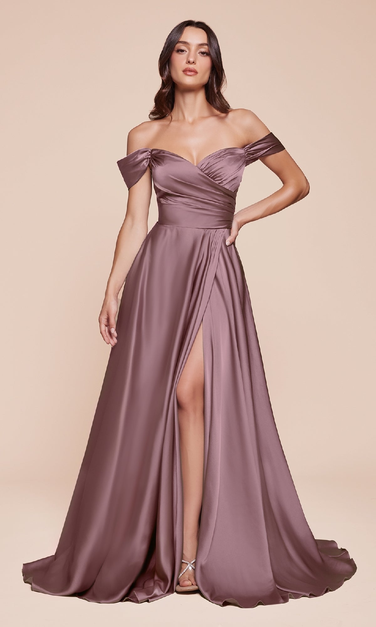 A woman models the Ladivine 7493-1, an off-the-shoulder mauve satin prom dress with a sweetheart neckline, fitted bodice, and thigh-high slit, posed against a plain beige background.