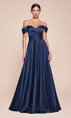 A woman models the Empire-Waist Plus-Size Long Prom Dress 7493C in navy blue satin, featuring an off-the-shoulder, floor-length design, standing against a plain beige background.