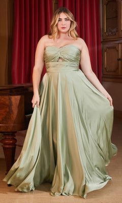 A woman in the Plus-Size Strapless Sweetheart Prom Dress 7496C, made of light green satin, stands indoors holding her skirt, with red curtains and wooden furniture in the background.