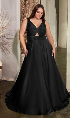 A woman stands indoors beside a decorative plant, wearing the Twist-Front Long Plus-Size Prom Dress 7497C— a floor-length, sleeveless black dress with a pleated bodice and V-neckline.