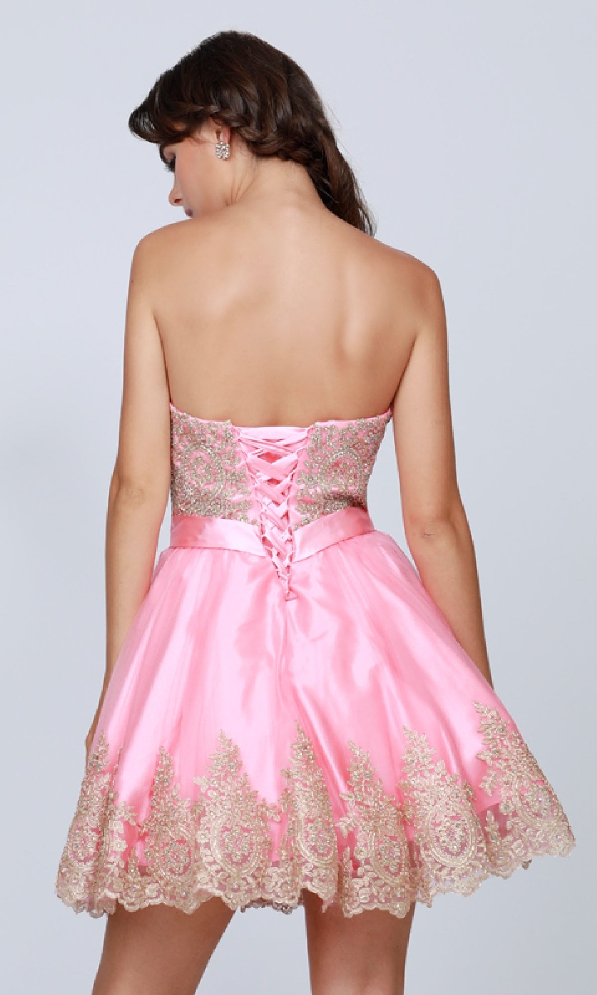 A woman facing away from the camera wears the Short Hoco Dress: Juliet 759, featuring a strapless neckline, gold embroidery, an a-line skirt, and lace-up back detail.