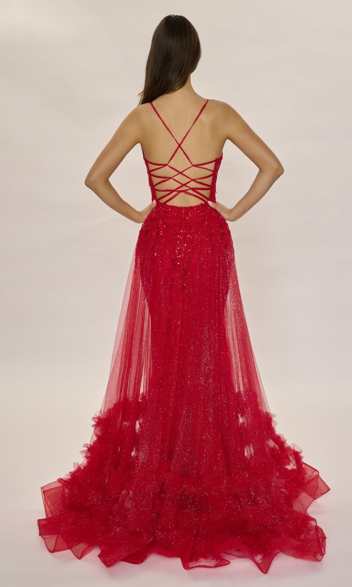 A person stands with their back to the camera wearing the Nina Canacci 7607, a long formal dress with sequins, a strappy back, fitted silhouette, and elegant tulle accents.