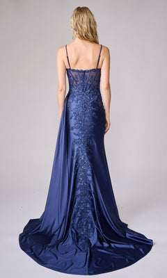 A woman stands with her back to the camera, wearing the Nina Canacci 7655—a floor-length navy blue satin formal dress featuring spaghetti straps and intricate embroidery down the back.
